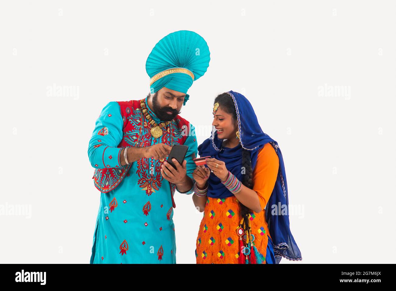 Un Bhangra e UN ballerino di Giddha che discutono i biils che hanno un mobile e una carta di credito in mano. Foto Stock