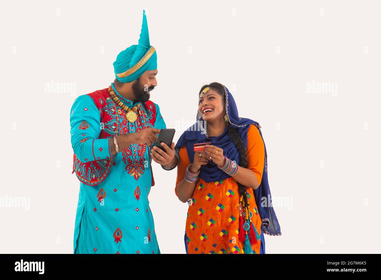 Un Bhangra e UN ballerino di Giddha che discutono giocosamente dei biils che hanno una carta di credito e del mobile in mano. Foto Stock