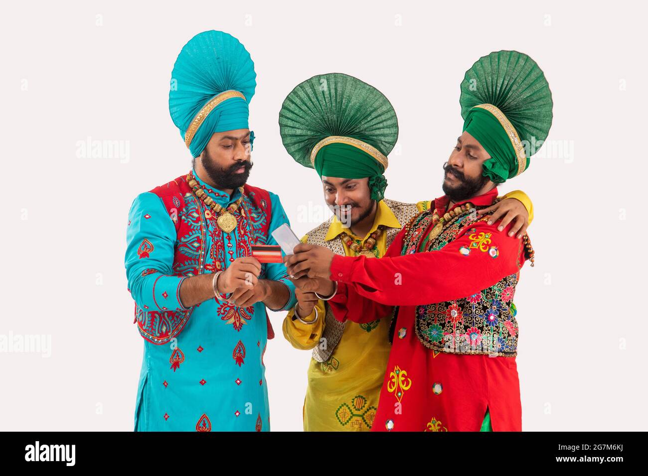 Un gruppo di tre ballerini di Bhangra che discutono le fatture con un telefono e una carta di credito in mano. Foto Stock