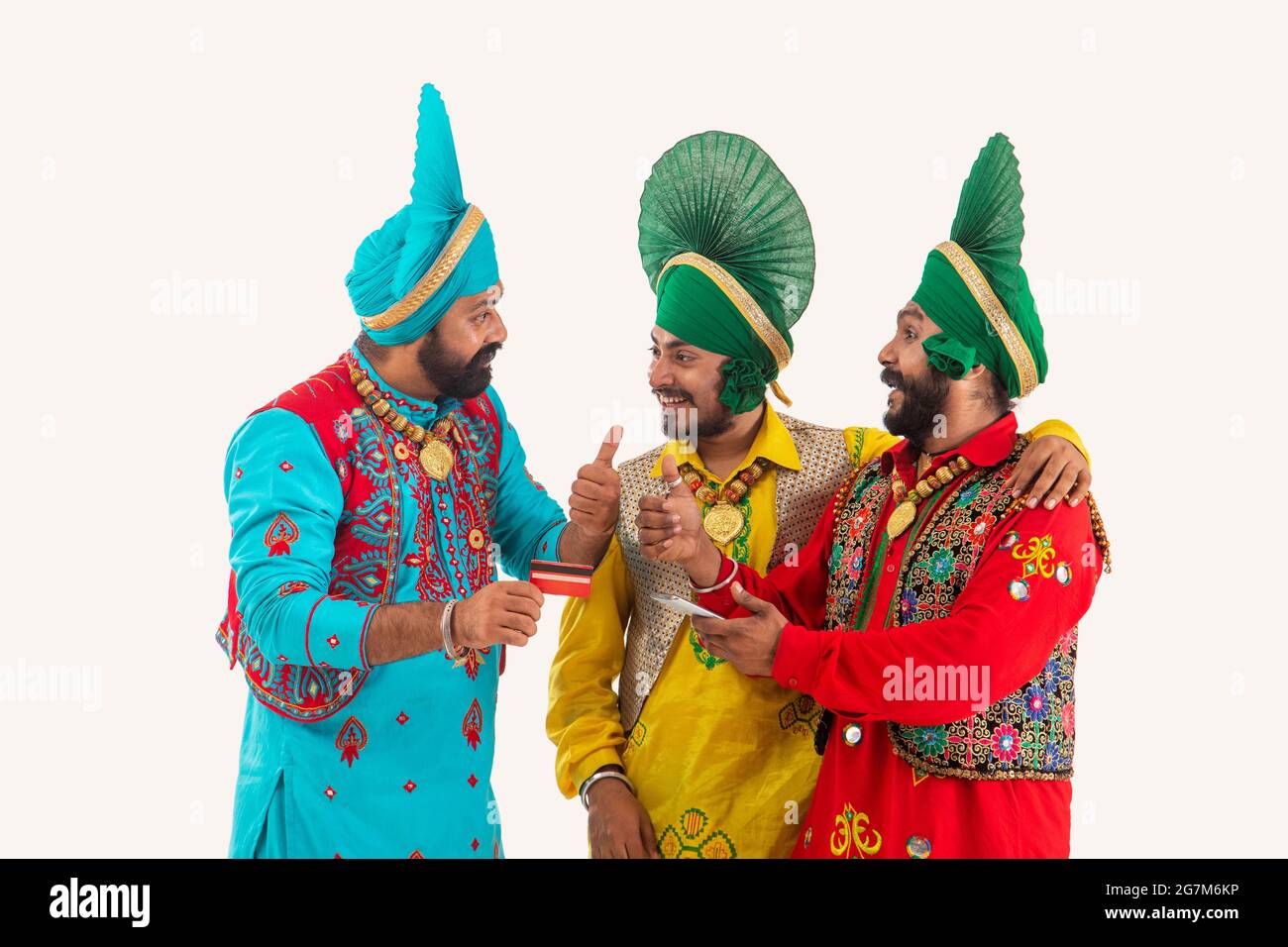 Un gruppo di tre ballerini Bhangra che discutono giocosamente le fatture con un telefono e una carta di credito in mano. Foto Stock