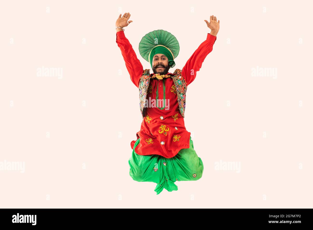 Un ballerino di Bhangra che salta con le mani per mostrare un passo di danza. Foto Stock