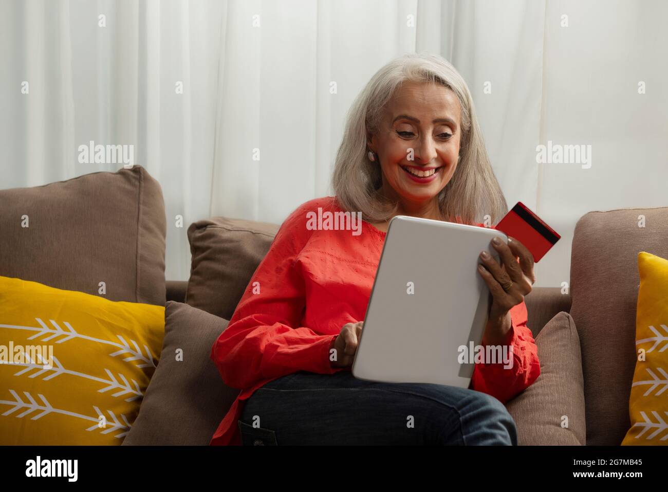 Una vecchia donna che effettua un ordine sul suo laptop con carta di credito. Foto Stock