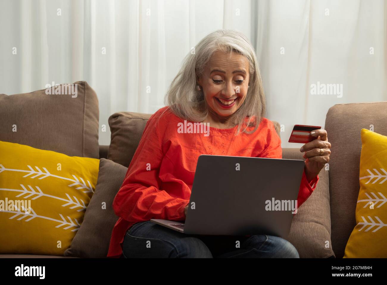 Una vecchia donna che effettua un ordine sul suo laptop con carta di credito. Foto Stock