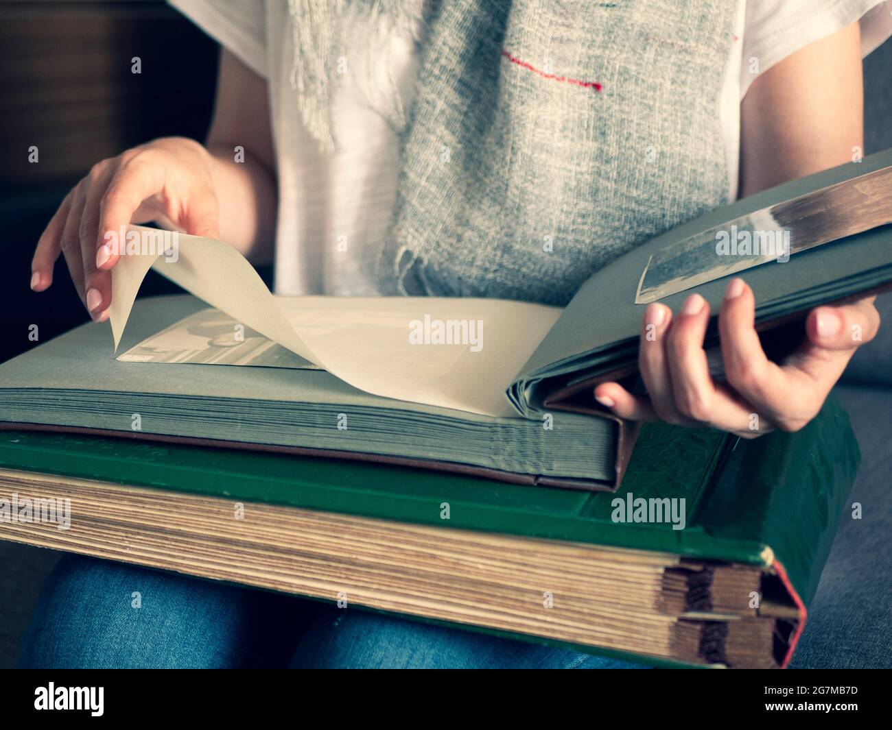 Donna sta guardando le foto in bianco e nero sulle pagine del suo album fotografico di famiglia. Capovolgere le pagine del vecchio album fotografico Foto Stock