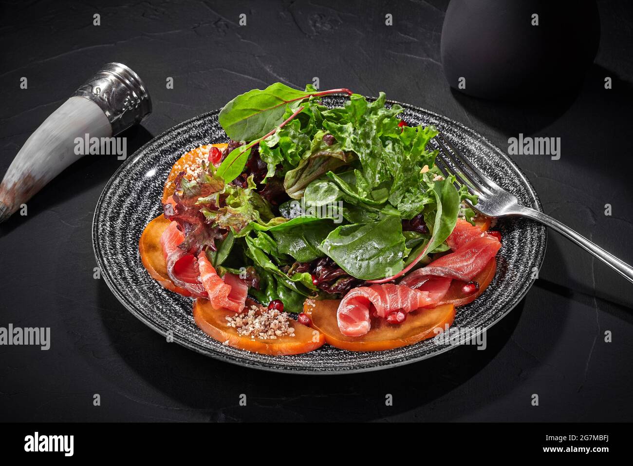 Insalata di verdure, persimmoni e salmone salato con melograno e noci Foto Stock