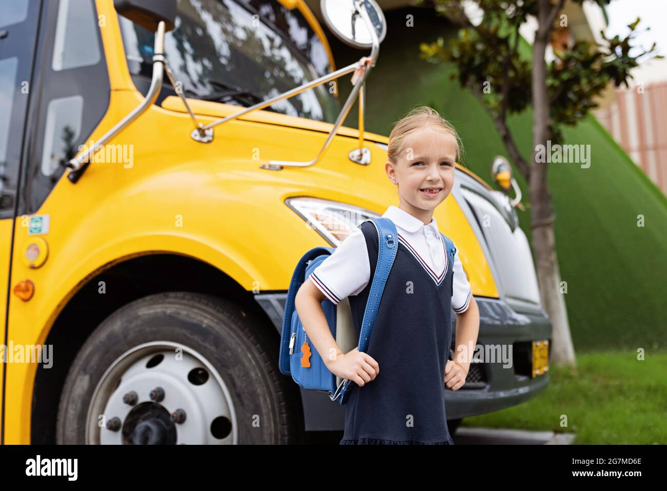 Ritorno a scuola. Bambina della scuola elementare all'aperto vicino al bus giallo. Kid Going imparare nuove cose 1 settembre Foto Stock
