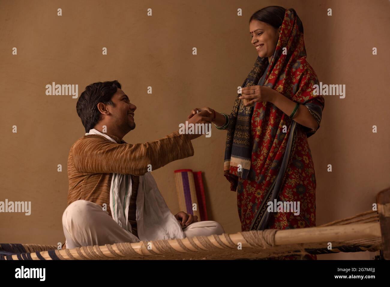 UNA MOGLIE RURALE CHE DÀ UN BICCHIERE DI TÈ AL MARITO Foto Stock