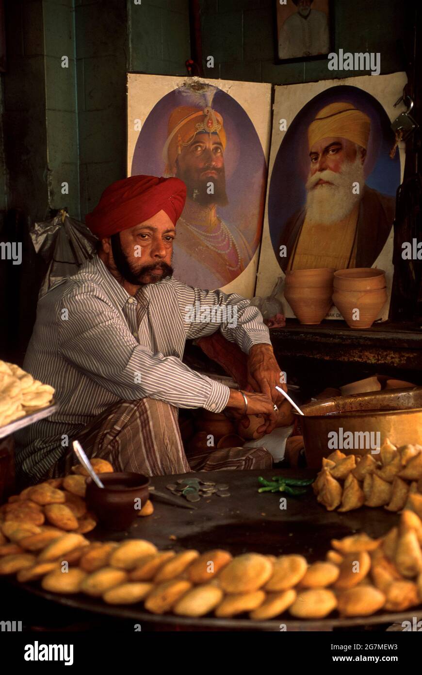 Un uomo Sikh che vende bhajis dal suo stallo di strada Foto Stock