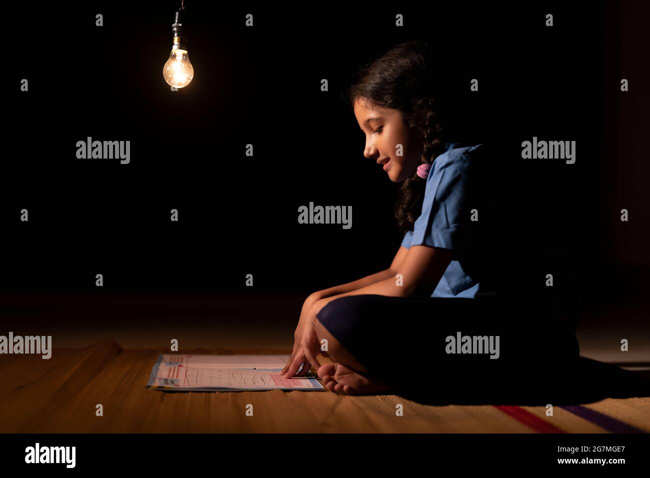 RITRATTO DI UNA RAGAZZA RURALE CHE STUDIA SOTTO LA LAMPADA DI NOTTE Foto Stock