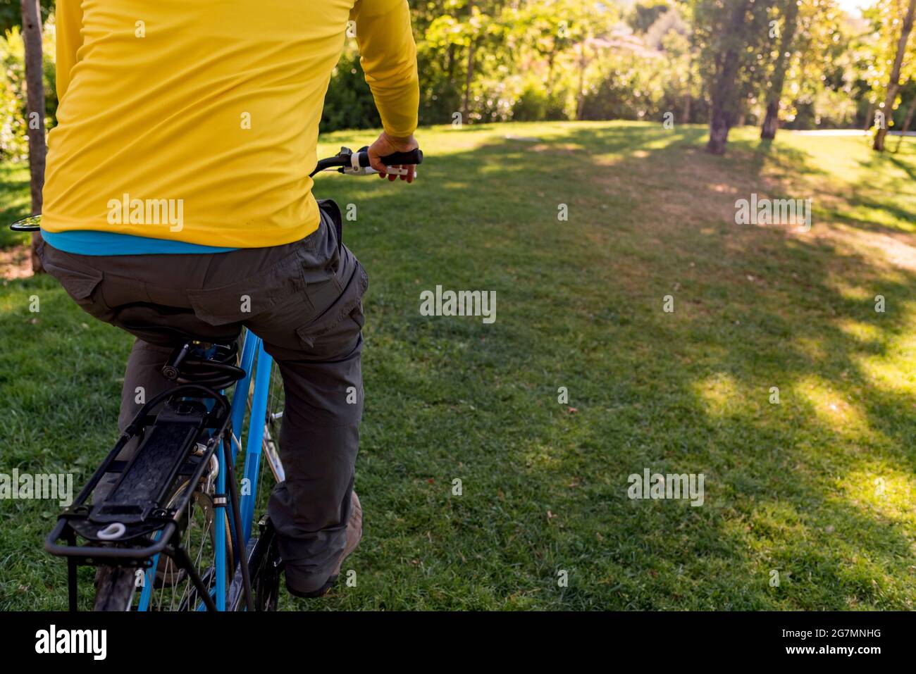 Uomo irriconoscibile nel parco con la sua bicicletta. Foto Stock