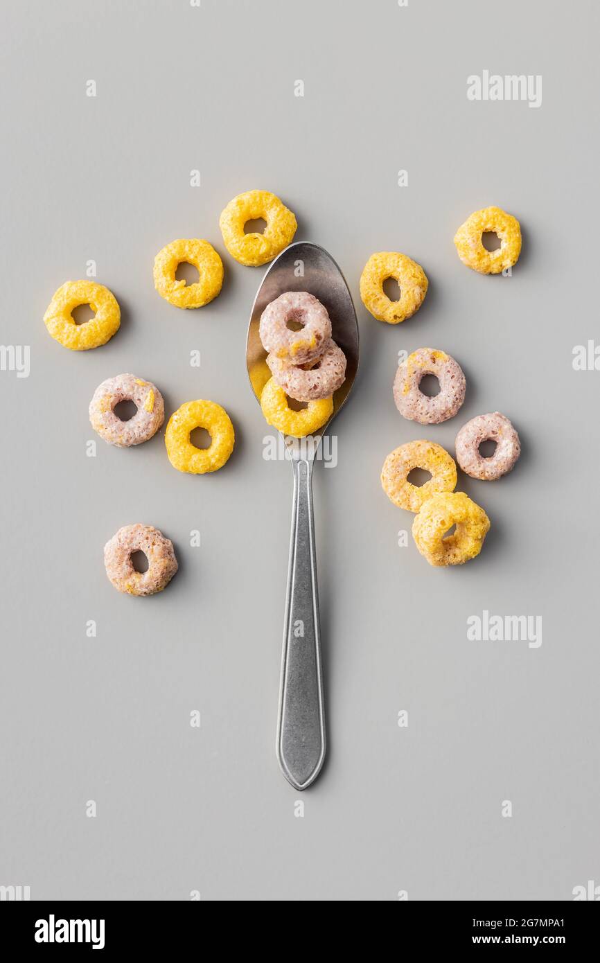 Colorati anelli di cereali in cucchiaio su sfondo grigio. Vista dall'alto. Foto Stock