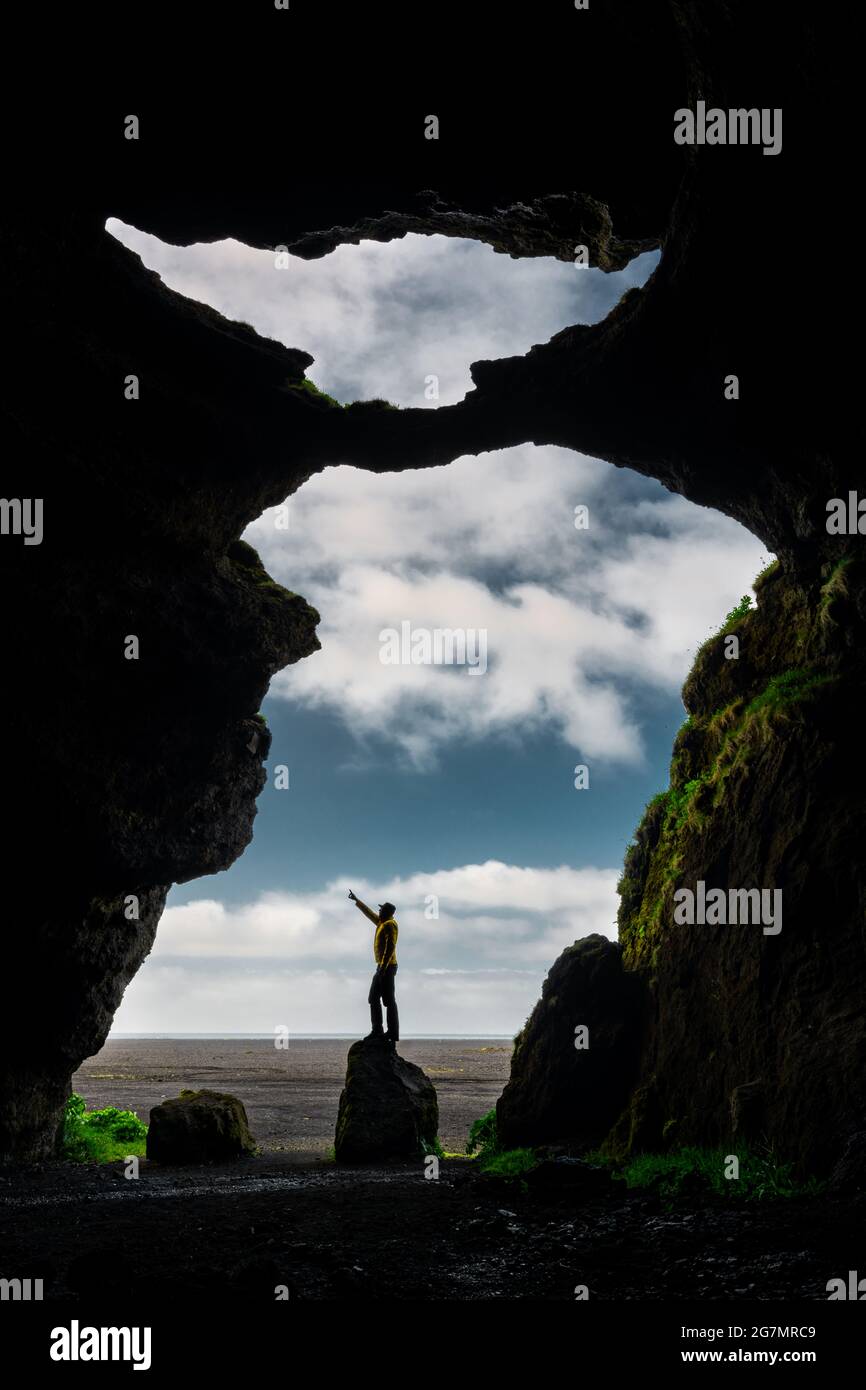 Persona in piedi su una roccia nella famosa Grotta di Yoda in Islanda. Foto Stock