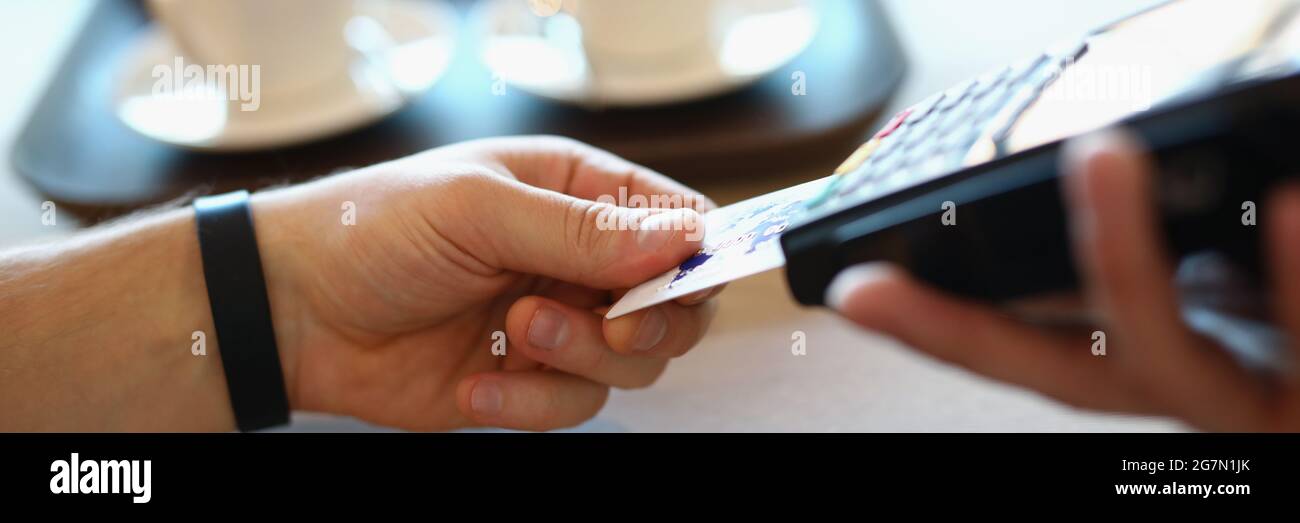 La mano maschile inserisce la carta di credito in plastica nel terminale di pagamento Foto Stock