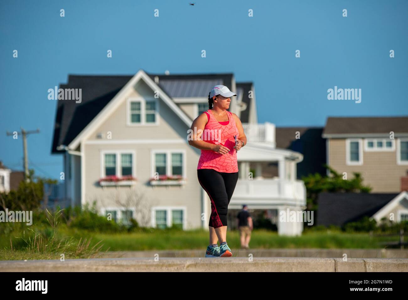 North Wildwood, Stati Uniti. 15 luglio 2021. Una donna cammina sulla paratia di cemento lungo l'Oceano Atlantico in un caldo giorno d'estate Giovedi, 15 luglio 2021 a in North Wildwood, New Jersey. Le temperature sono attese negli anni '90 per tutto il resto di questa settimana. Credit: William Thomas Cain/Alamy Live News Foto Stock