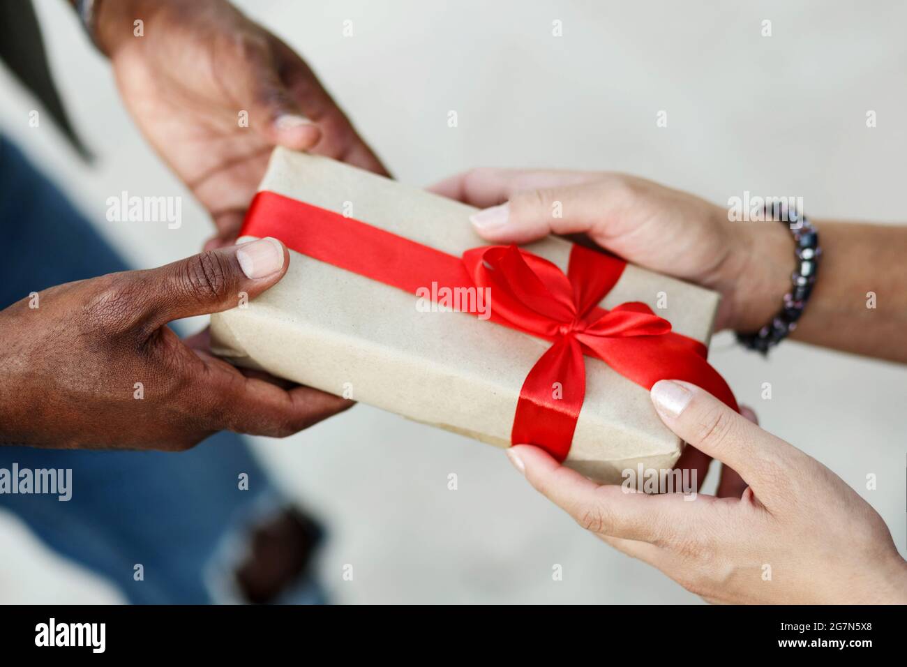 Primo piano le mani della coppia interracial . Uomo che dà il regalo di San Valentino alla sua donna, ragazza o moglie. Foto Stock