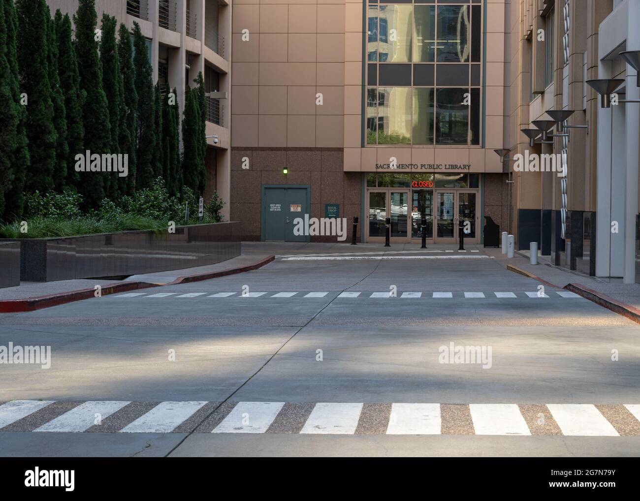 Lato anteriore della biblioteca pubblica di Sacramento, California, Stati Uniti, tra cui la strada, l'incrocio e gli edifici circostanti. Il segno dice chiuso . Foto Stock