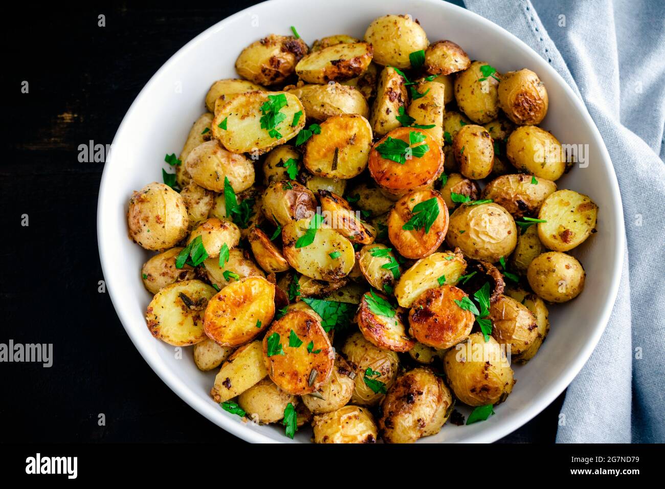 Patate arrosto alla senape alle erbe in un recipiente da portata: Patate arrosto all'oro Yukon in una ciotola di servizio in ceramica bianca Foto Stock