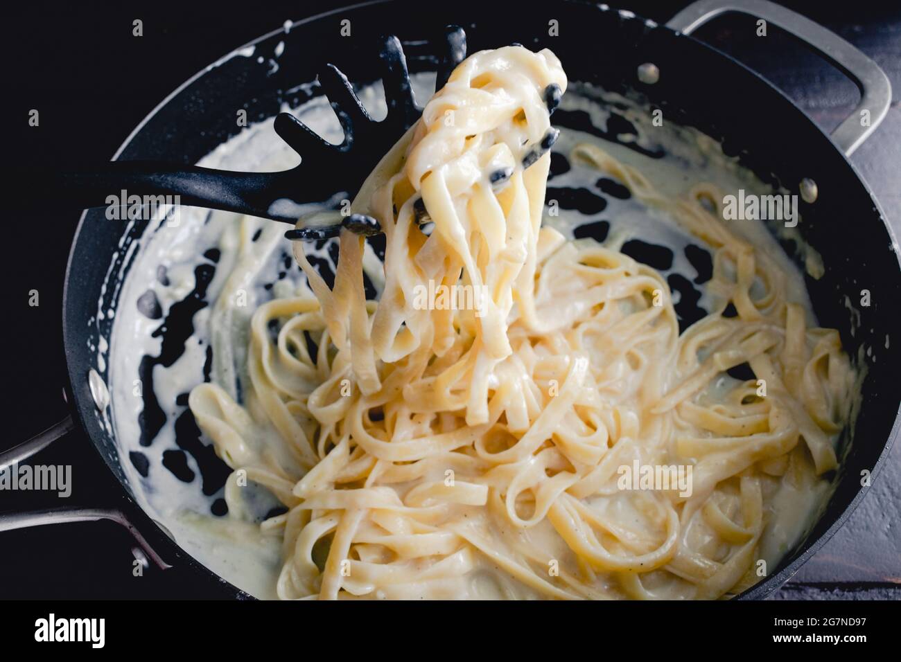 Fettuccine Alfredo in padella saltata: Tagliatelle preparate al momento in una cremosa salsa di parmigiano Foto Stock