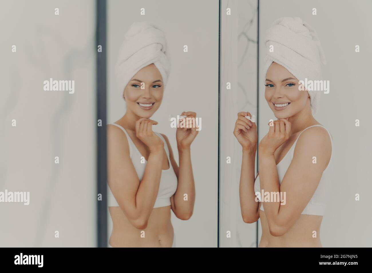 Bella donna riflessa nello specchio mentre spazzolando i suoi denti Foto Stock