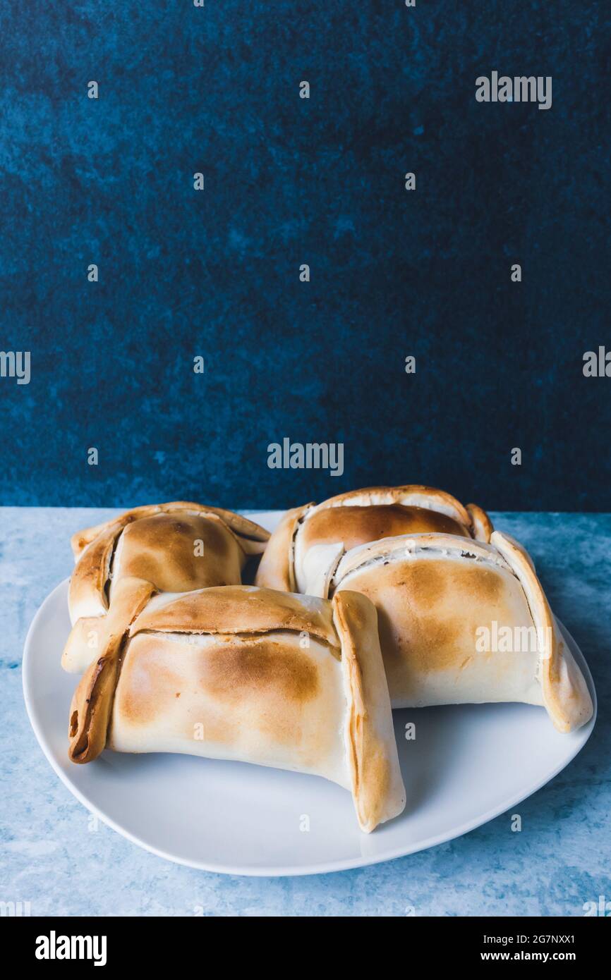 Empanadas cilene, a base di carne e cipolla. Sfondo blu. Foto Stock