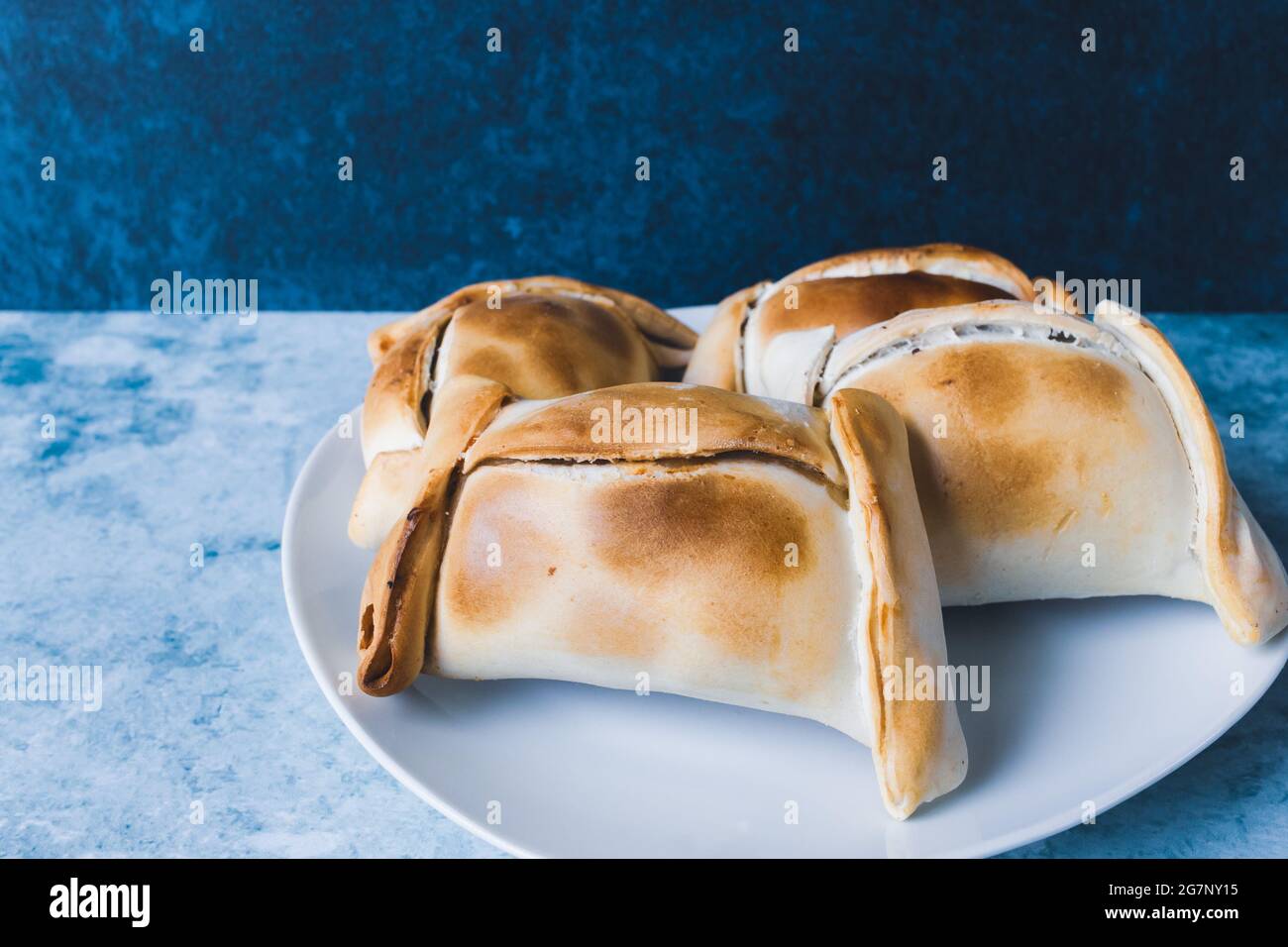 Empanadas cilene, a base di carne e cipolla. Sfondo blu. Foto Stock