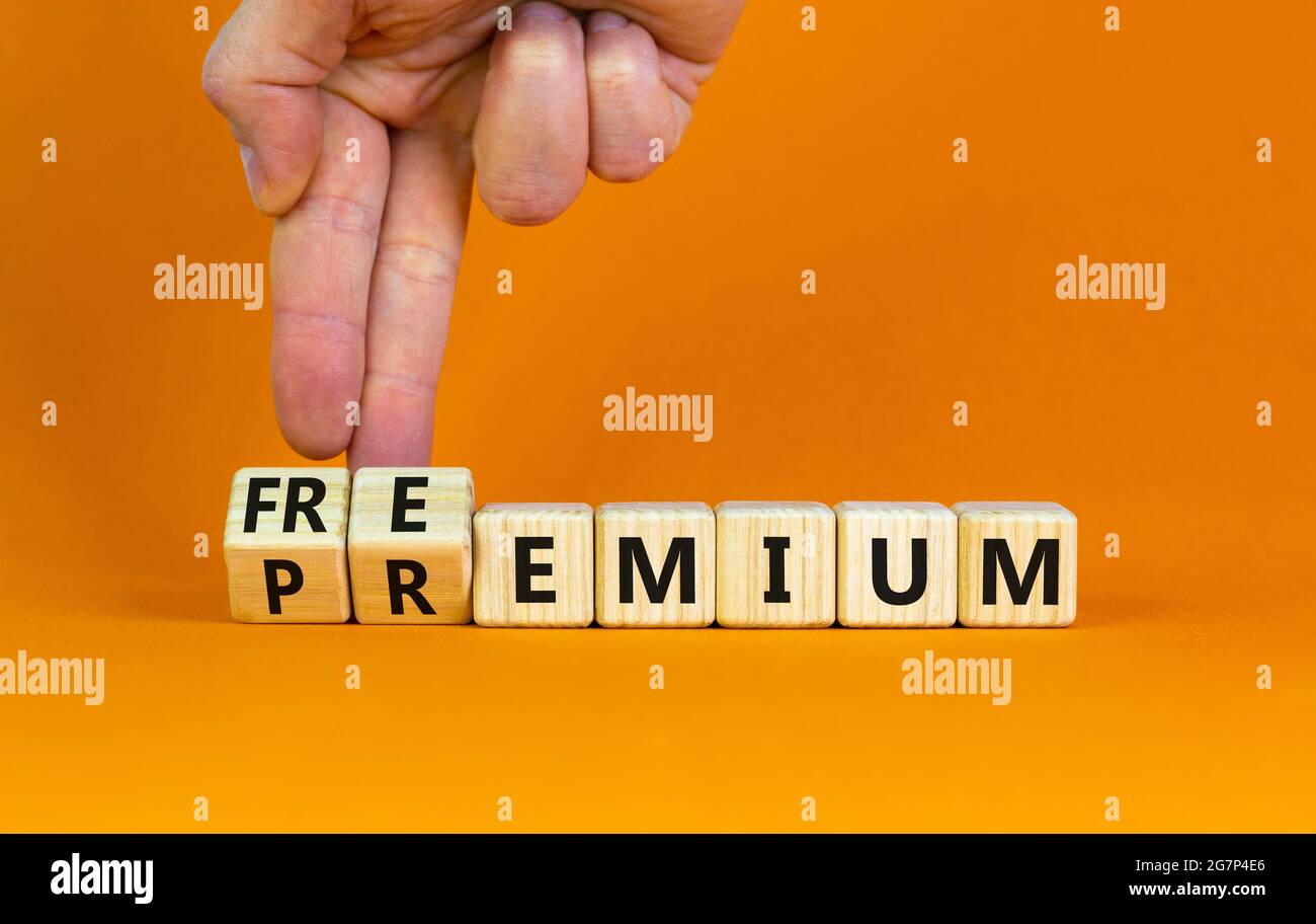 Simbolo Premium o freemium. Uomo d'affari trasforma i cubetti di legno e cambia la parola 'premium' in 'freemium'. Bellissimo sfondo arancione. Business, premiu Foto Stock