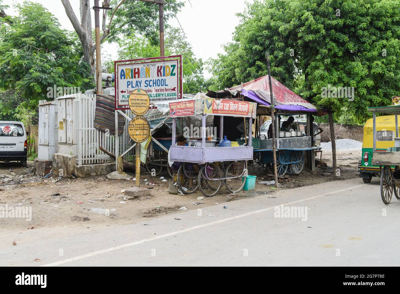 Venditore di strada sulla strada con un cartello per un prescolare in una sezione povera di Agra, con il Taj Mahal appena dietro l'angolo. Foto Stock