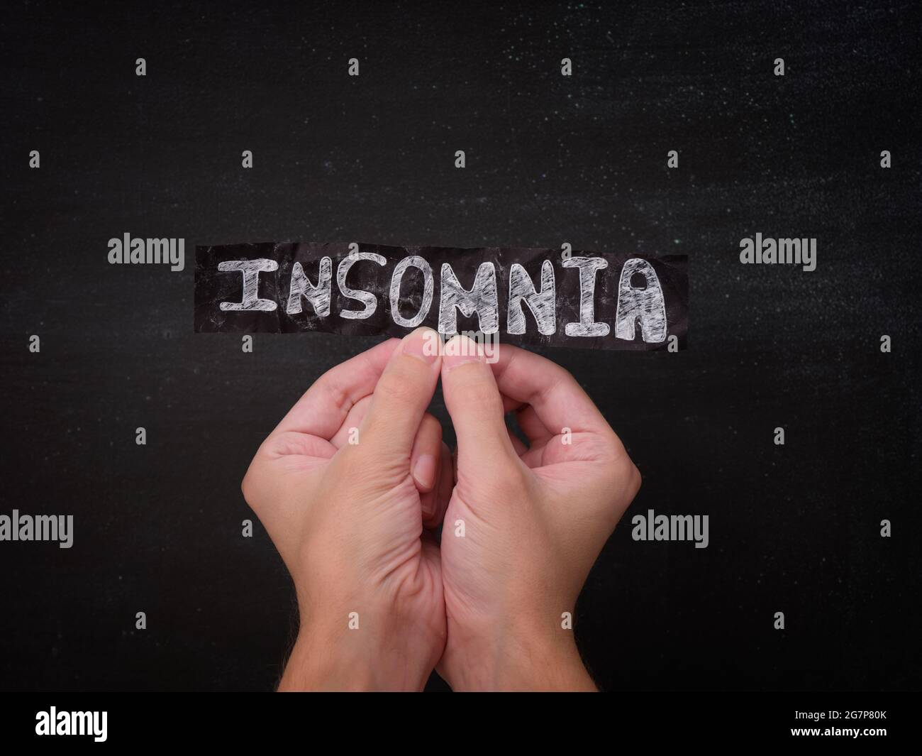 Una persona che tiene un pezzo di carta nero con la parola Insomnia su di esso nelle sue mani. Primo piano. Foto Stock
