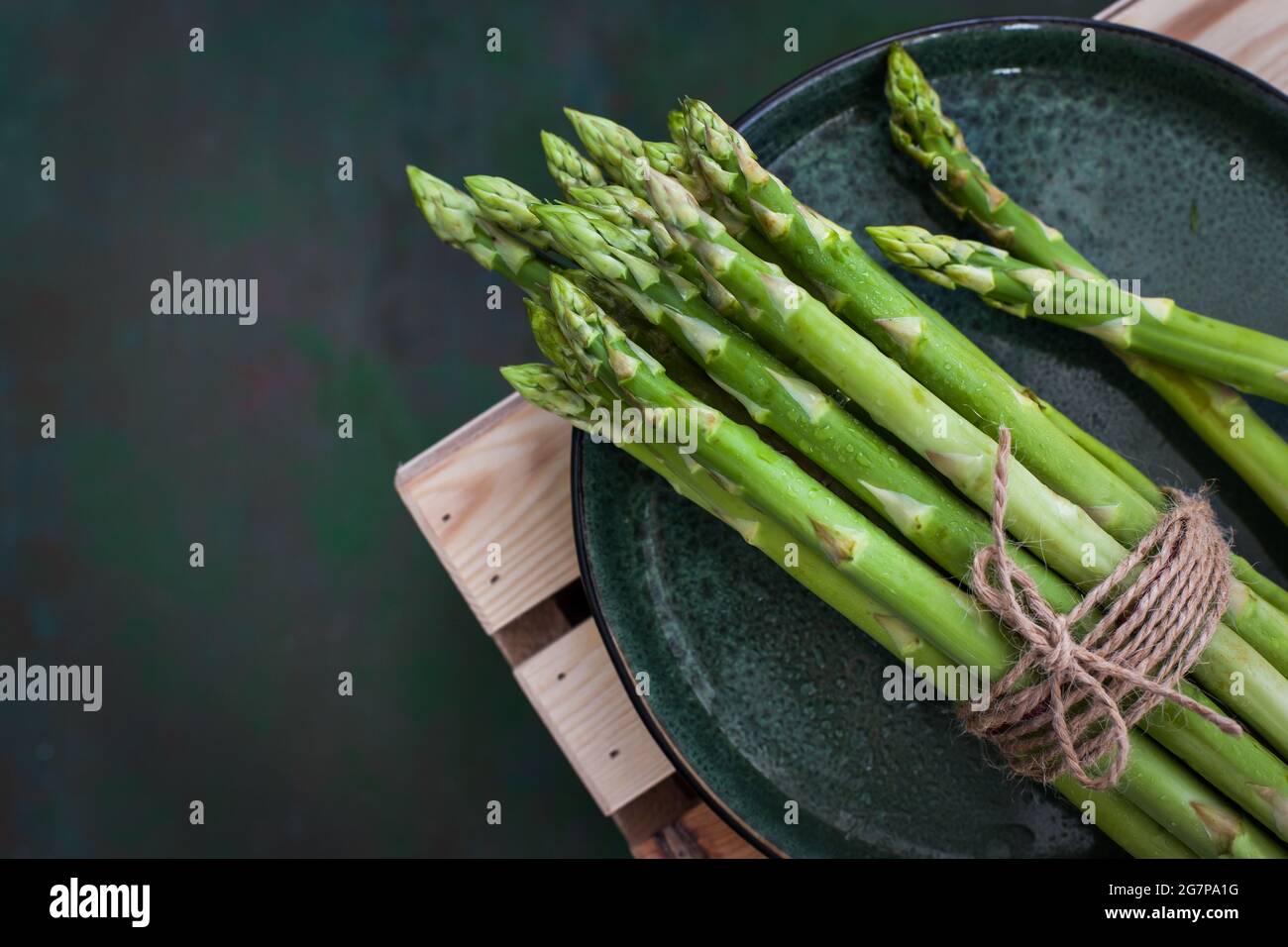 Asparagi freschi crudi su rustico sfondo verde, vista dall'alto Foto Stock