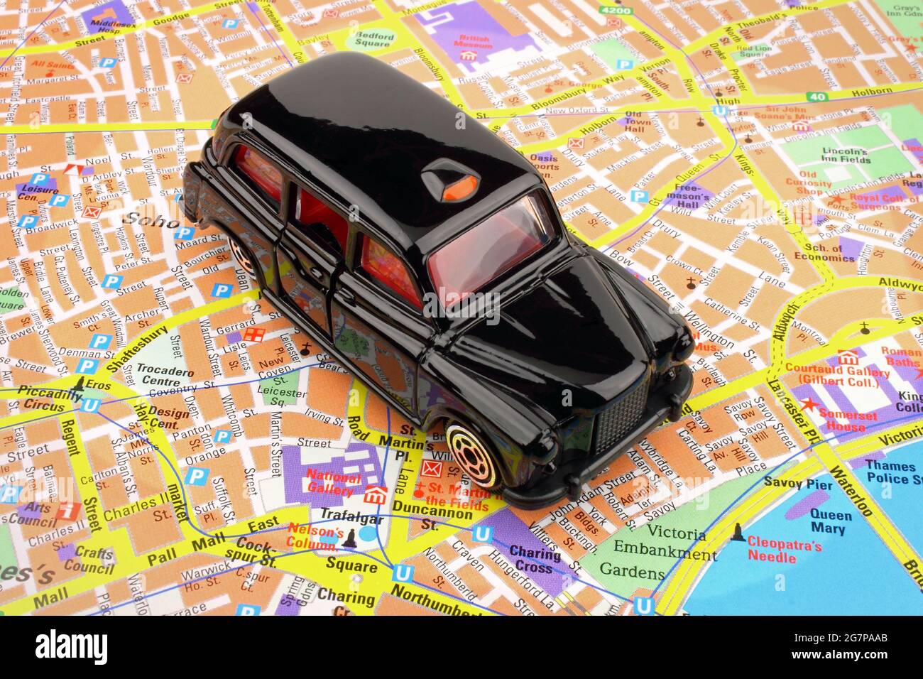 Un taxi nero, su una mappa della città di Londra. Foto Stock
