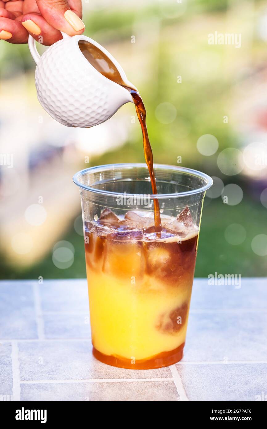 Preparazione del caffè Bumble - rinfrescante cocktail estivo ghiacciato con espresso, succo d'arancia, sciroppo di caramello e ghiaccio Foto Stock