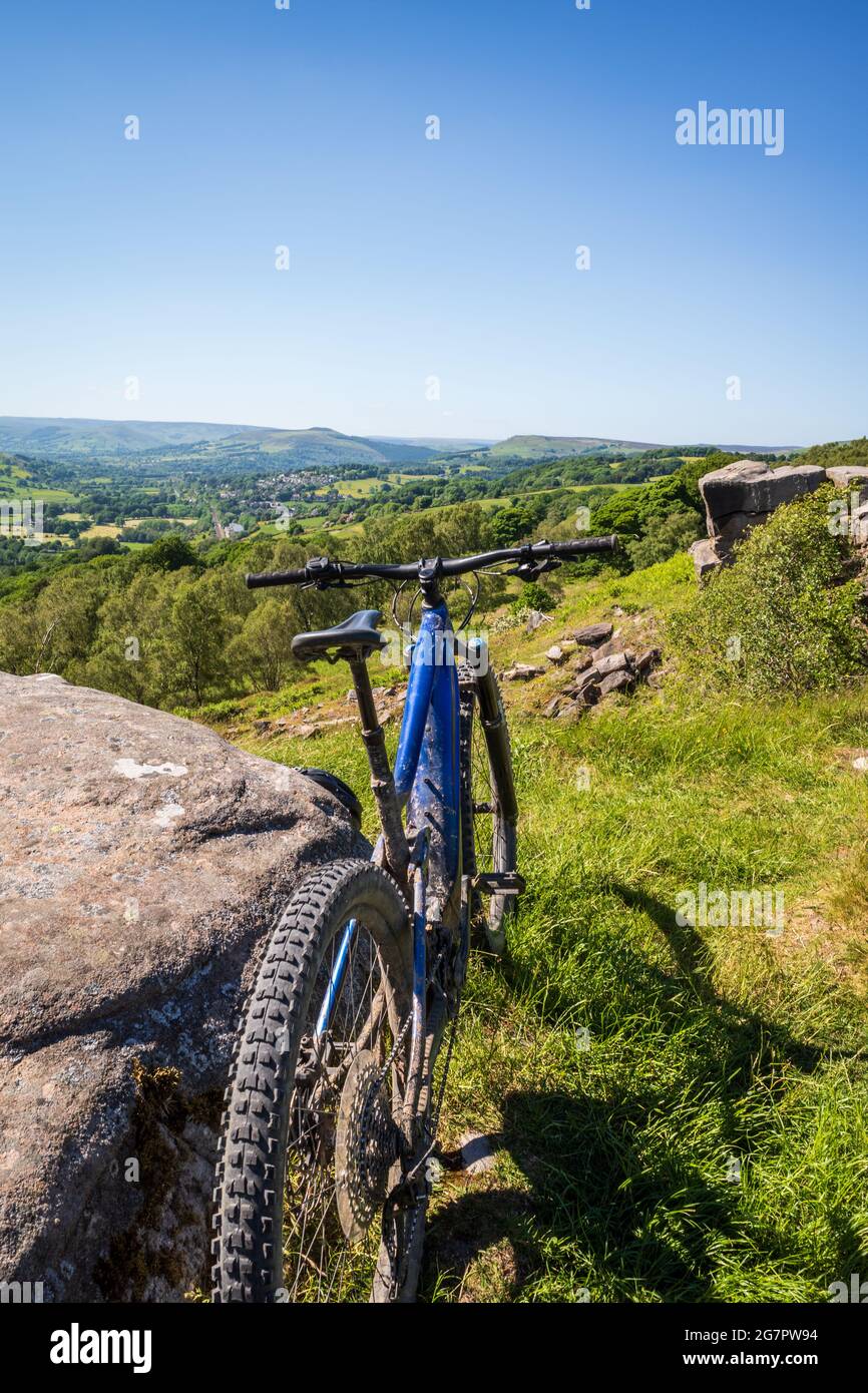 Primo piano su una bicicletta blu sportiva in piedi su una collina verde in una giornata di sole Foto Stock