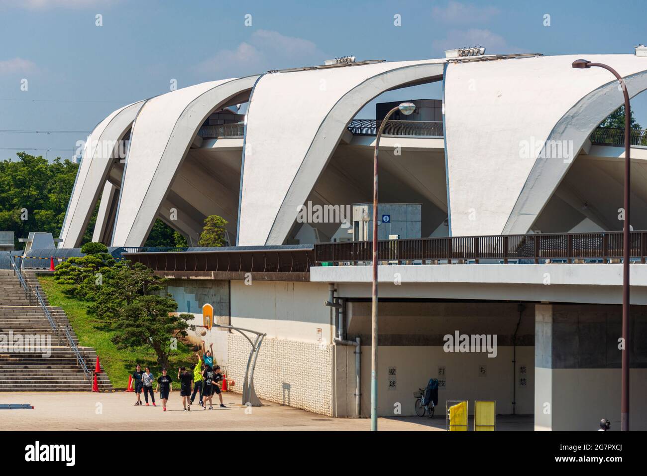 Lo stadio di atletica progettato da Masachika Murata sullo sfondo, i giovani giocano a basket all'interno del parco olimpico di Komazawa, Tokyo, il 10 giugno 2021. Il parco è stato costruito per le Olimpiadi del 1064 e rimane un popolare luogo di svago. Robert Gilhooly foto Foto Stock