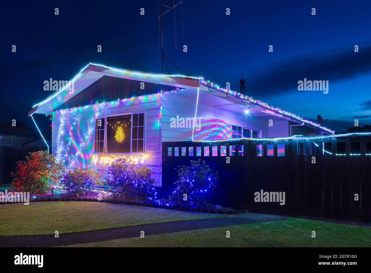 Una casa suburbana e giardino di notte, illuminato con luci di Natale Foto Stock