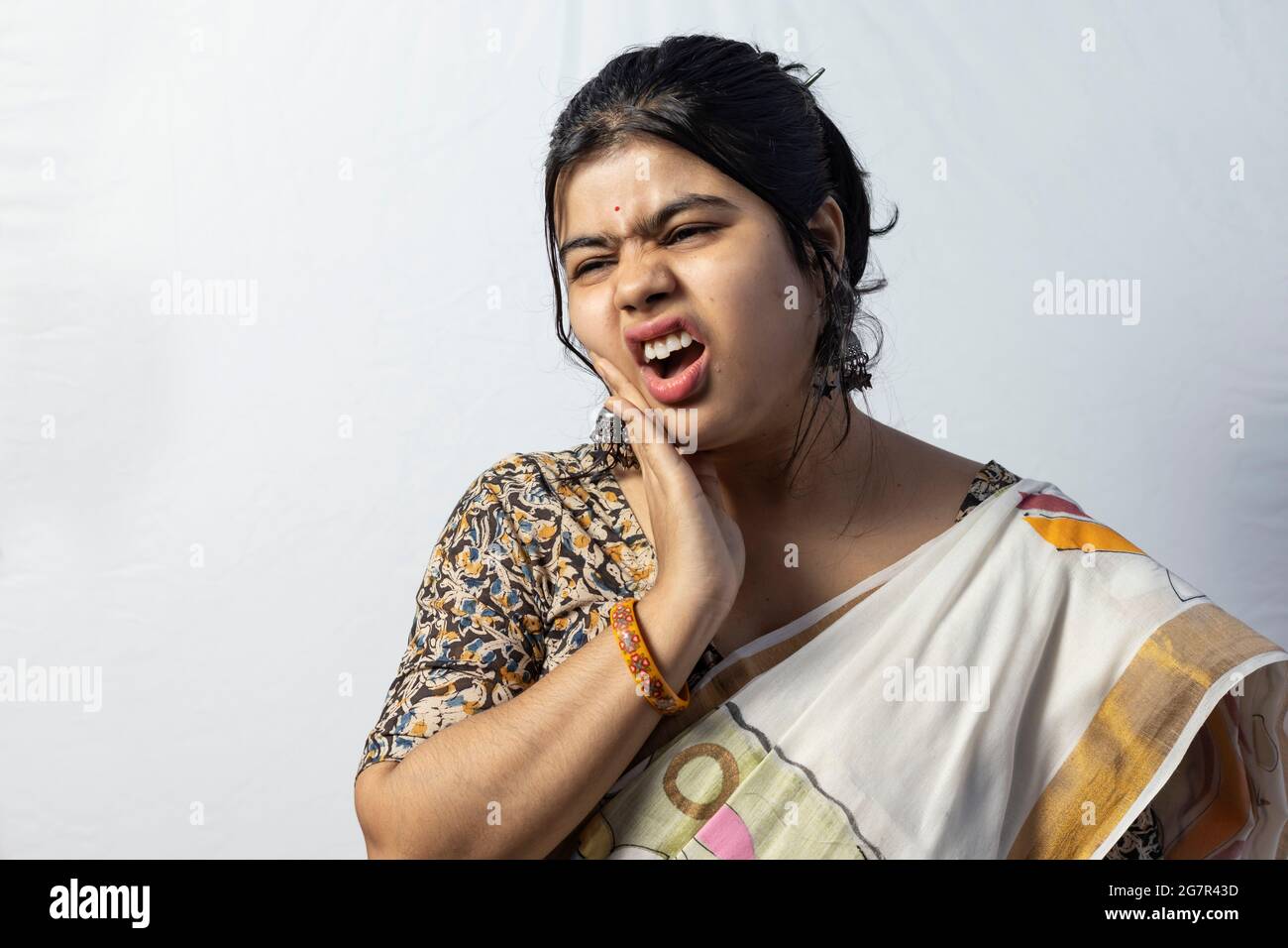 Isolato su sfondo bianco una femmina indiana in saree di fronte ai denti problema dolore su sfondo bianco Foto Stock