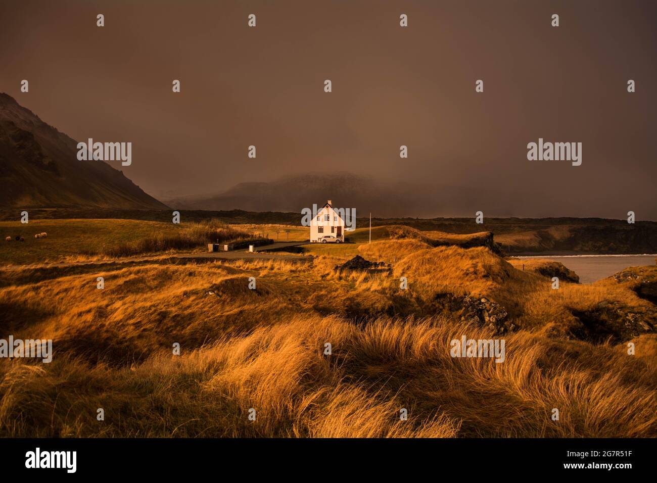 Una casa di campagna solitaria che si affaccia sul mare, avvistata durante un'escursione intorno alla periferia di Arnarstapi, una piccola città sulla costa occidentale dell'Islanda Foto Stock