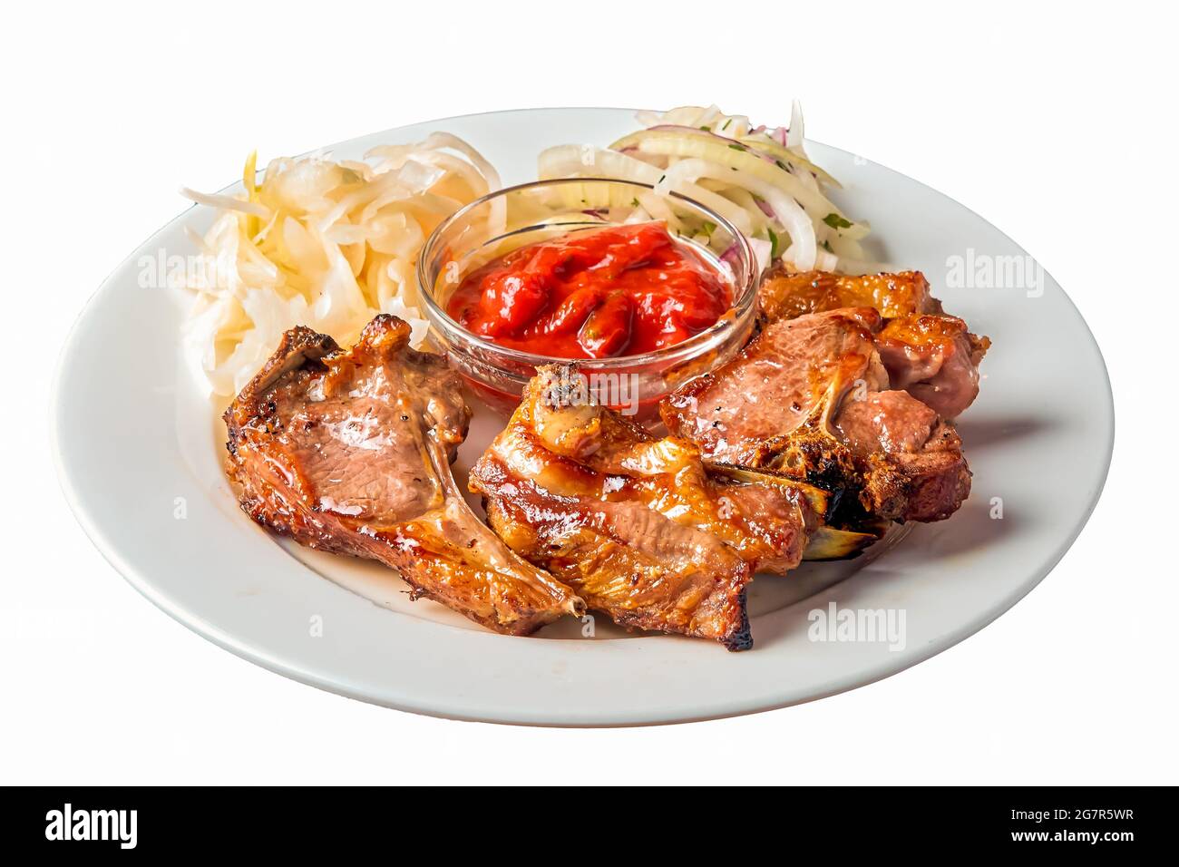 un kebab di agnello su un osso giace su un piatto su uno sfondo bianco isolato Foto Stock