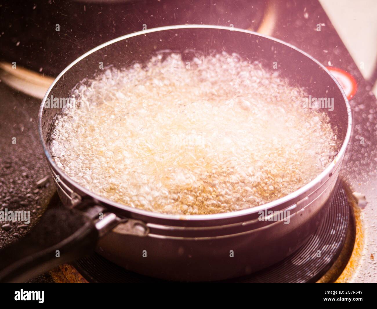 Primo piano di friggere le patatine fritte nella friggitrice in olio caldo sulla stufa elettrica in cucina. Produzione di patatine fritte fatte in casa. Foto Stock