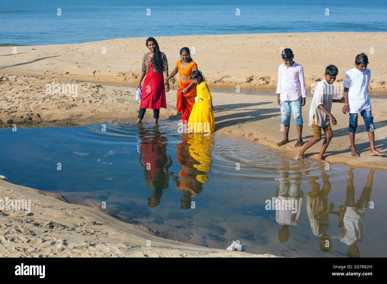 I ragazzi e le ragazze indiane giocano ai margini di una piscina d'acqua sulla spiaggia di Varkala, Kerala, India Foto Stock