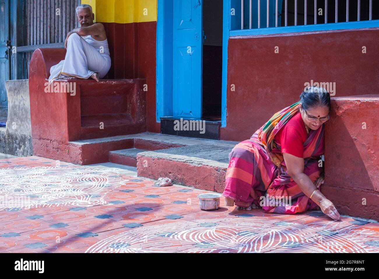 Anziana donna indiana pittura un kolam sul pavimento fuori della sua casa, Fort Kochi (Cochin), Kerala, India Foto Stock