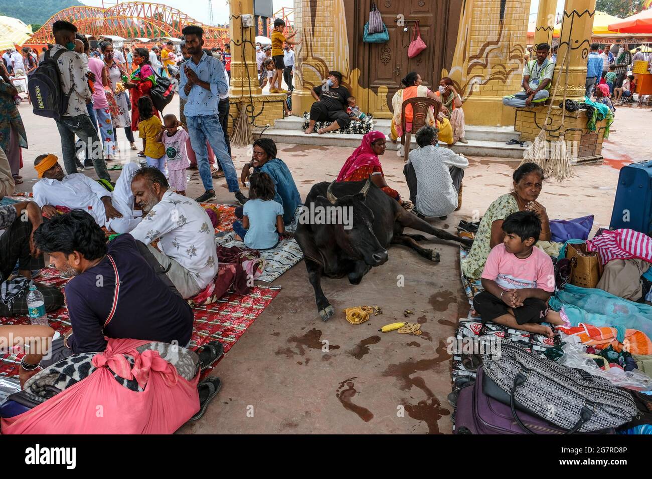 Haridwar, India - 2021 luglio: Pellegrini che riposano vicino ad una mucca vicino al fiume Gange in Haridwar il 14 luglio 2021 a Uttarakhand, India. Foto Stock