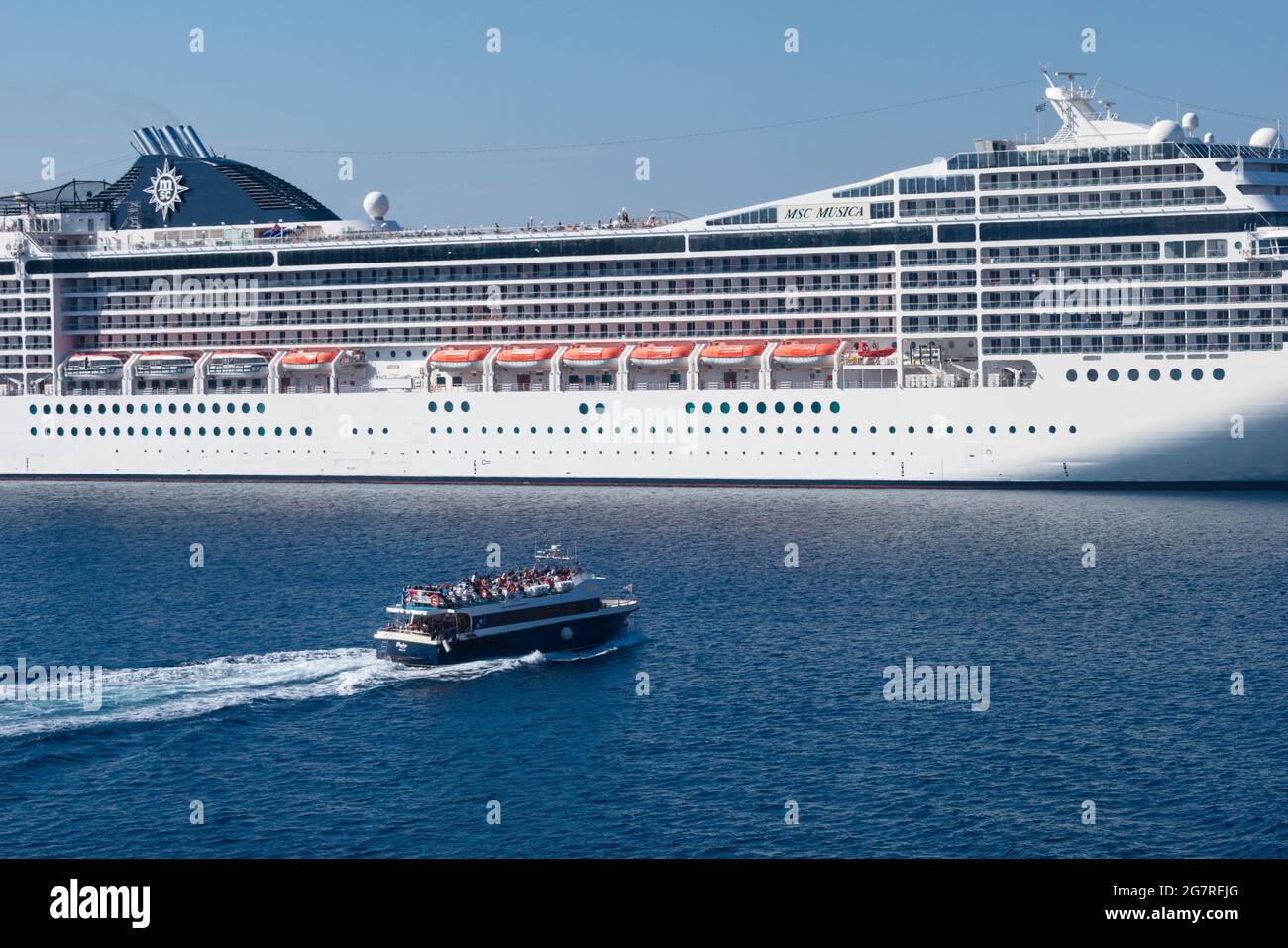 Isola di Santorini - Grecia - 3 ottobre 2018 : grande nave da crociera ormeggiata in mare. Piccola barca a vela in primo piano. Foto Stock