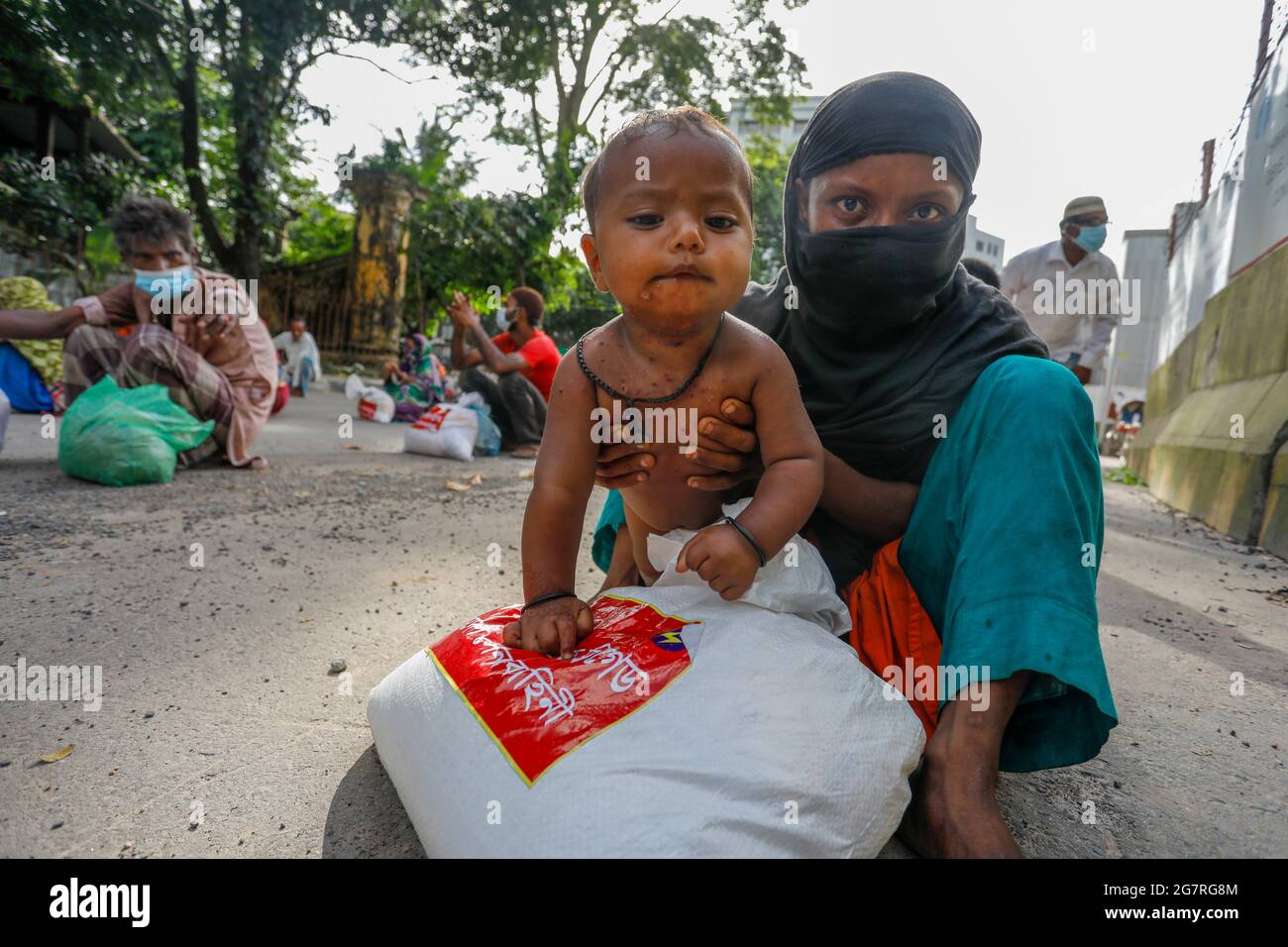 Le persone a basso reddito ricevono gli alimenti di emergenza forniti dall'esercito del Bangladesh durante il blocco nazionale per frenare la diffusione del coronavirus (COVID-19) Foto Stock