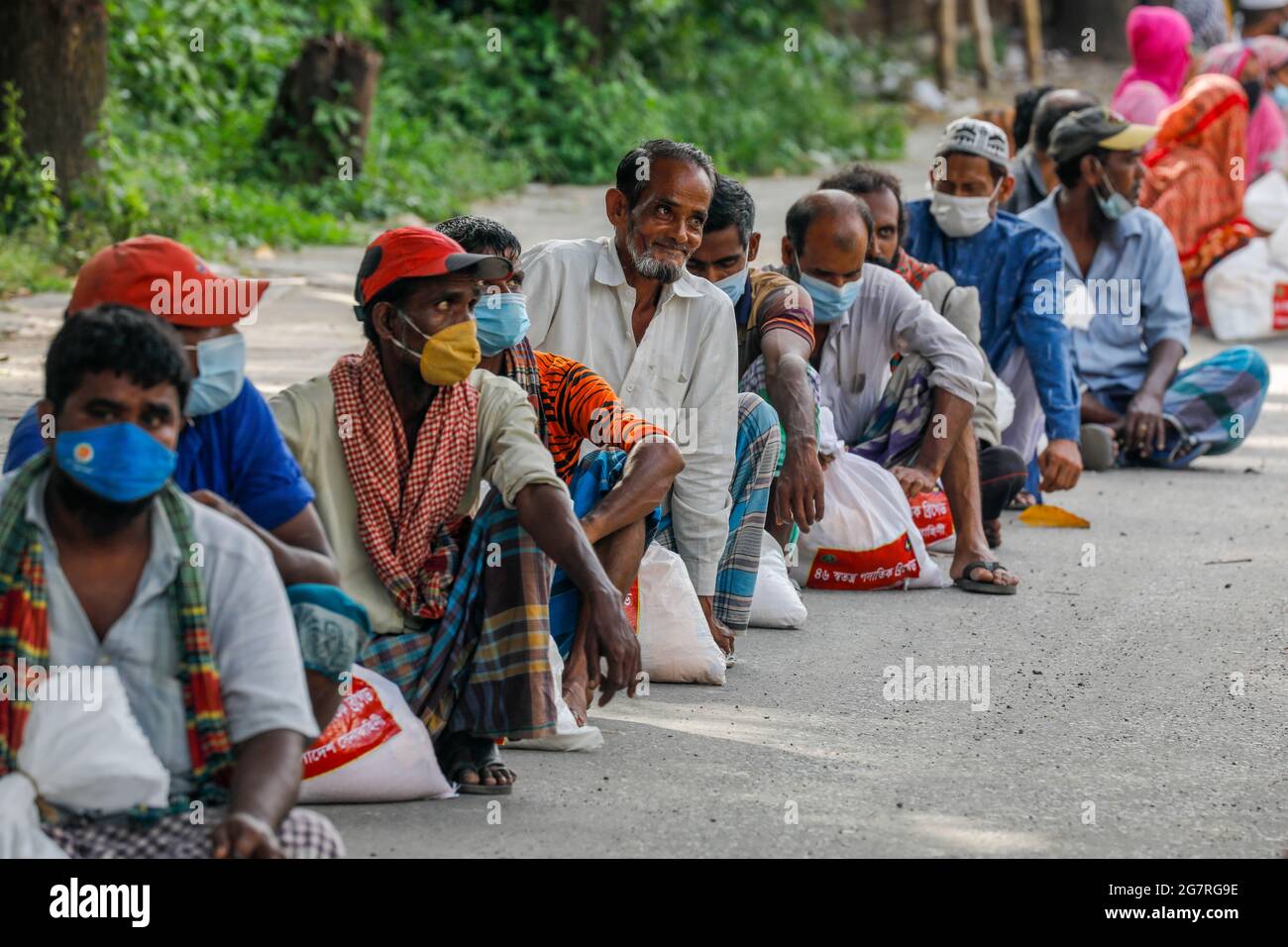 Le persone a basso reddito ricevono gli alimenti di emergenza forniti dall'esercito del Bangladesh durante il blocco nazionale per frenare la diffusione del coronavirus (COVID-19) Foto Stock