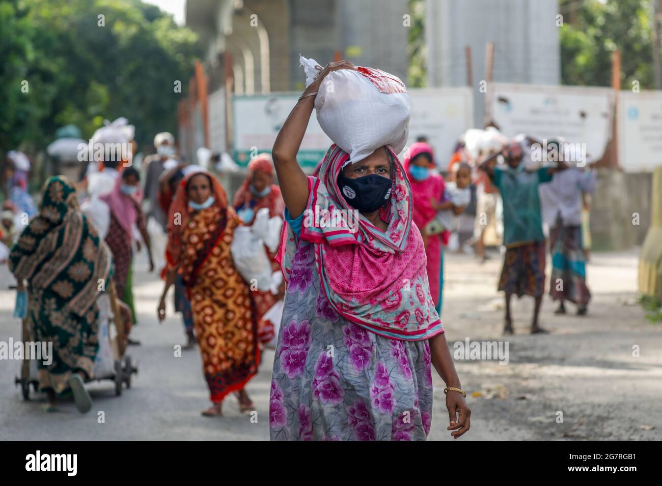 Le persone a basso reddito ricevono gli alimenti di emergenza forniti dall'esercito del Bangladesh durante il blocco nazionale per frenare la diffusione del coronavirus (COVID-19) Foto Stock