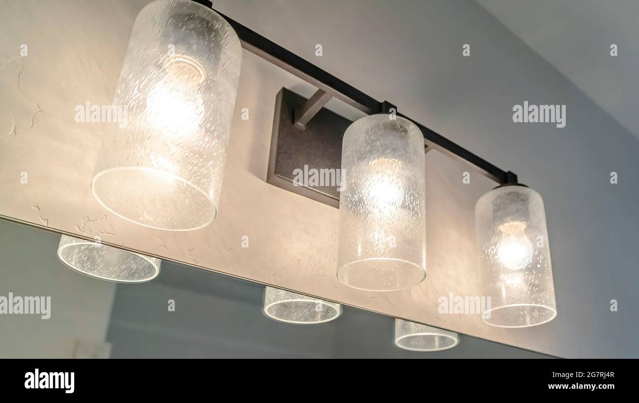 Pano lampada decorativa in vetro e grande specchio montato sulla parete di un bagno Foto Stock