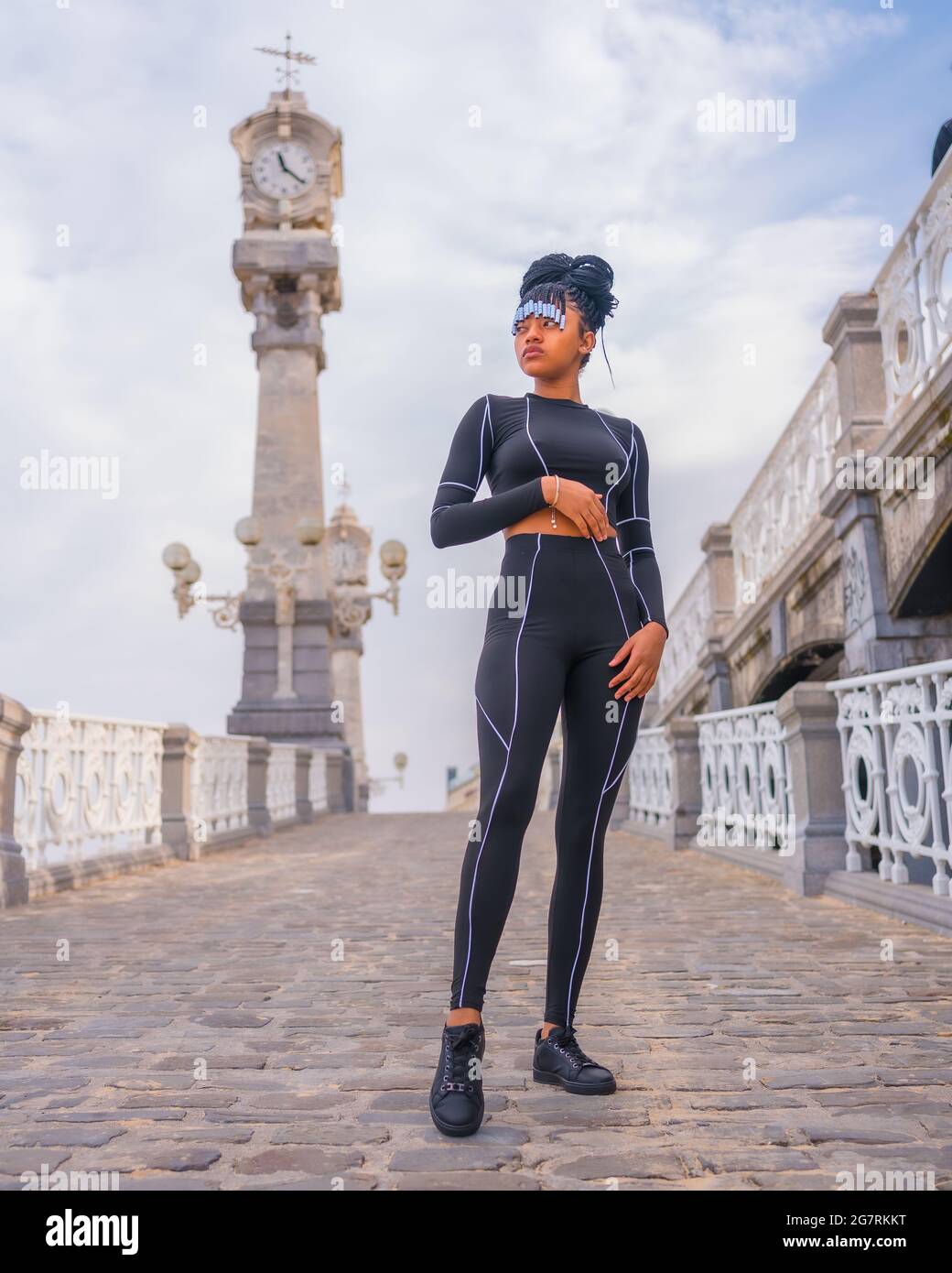 Dominicana femmina con trecce in un vestito corpo nero in piedi accanto a  un bellissimo orologio da spiaggia Foto stock - Alamy
