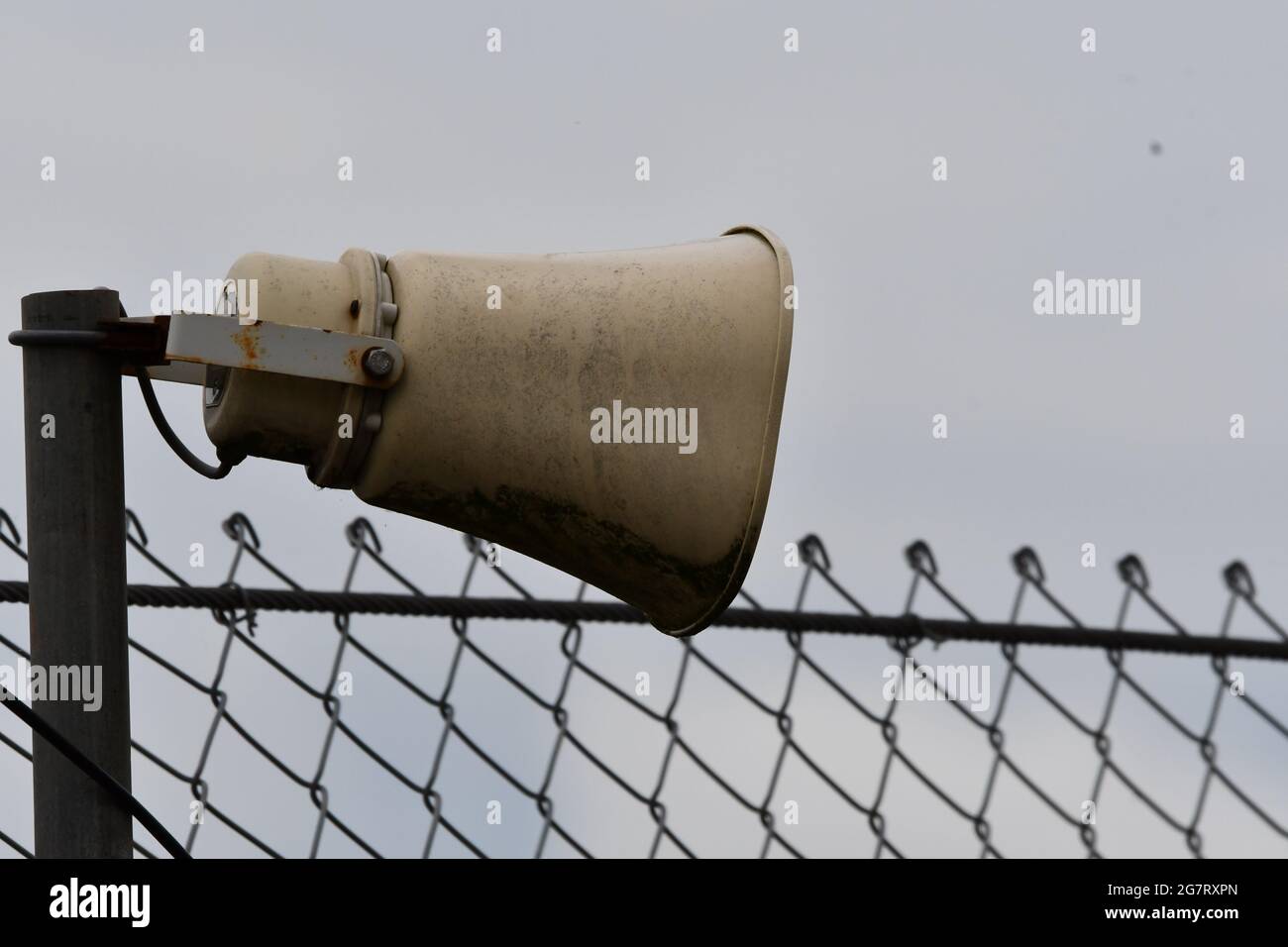 Un megafono intemperie, altoparlante di comunicazione pubblica accanto a una recinzione di sicurezza Foto Stock
