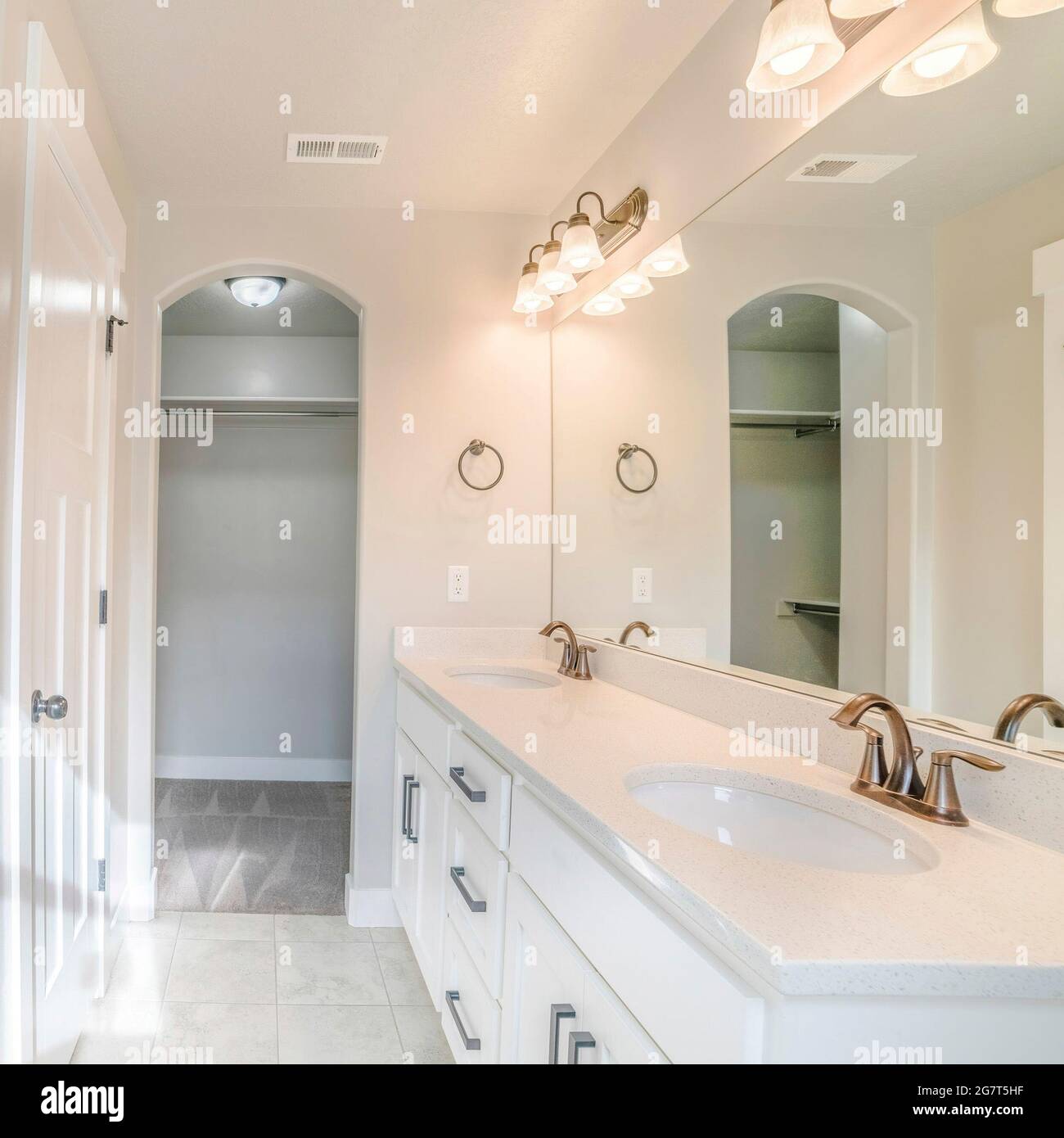Cornice quadrata interno di un bagno bianco con doccia con parete di vetro, lavabo e armadio vuoto Foto Stock
