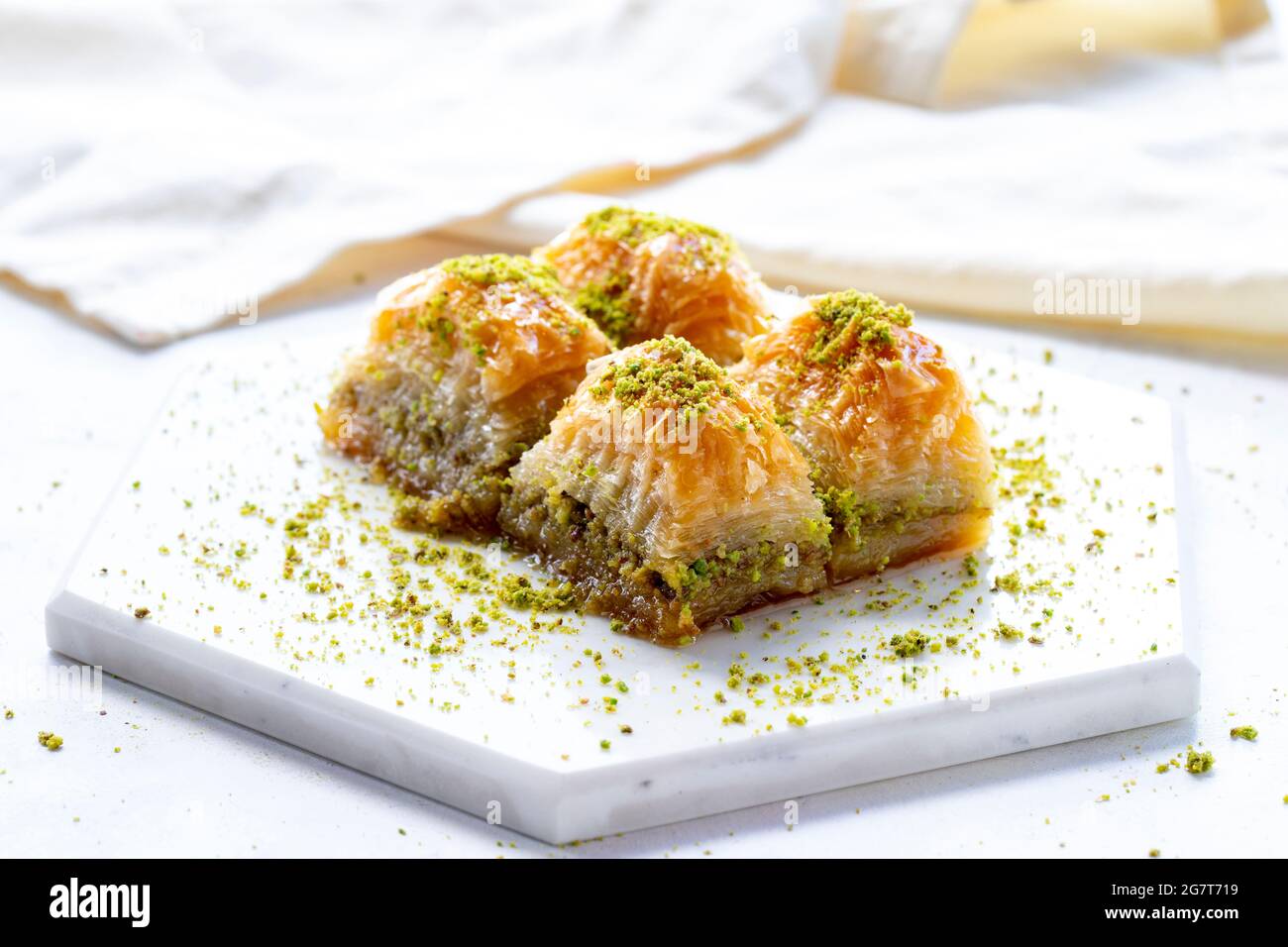 Baklava con pistacchio su sfondo bianco di legno. Baklava su pavimento in marmo Foto Stock